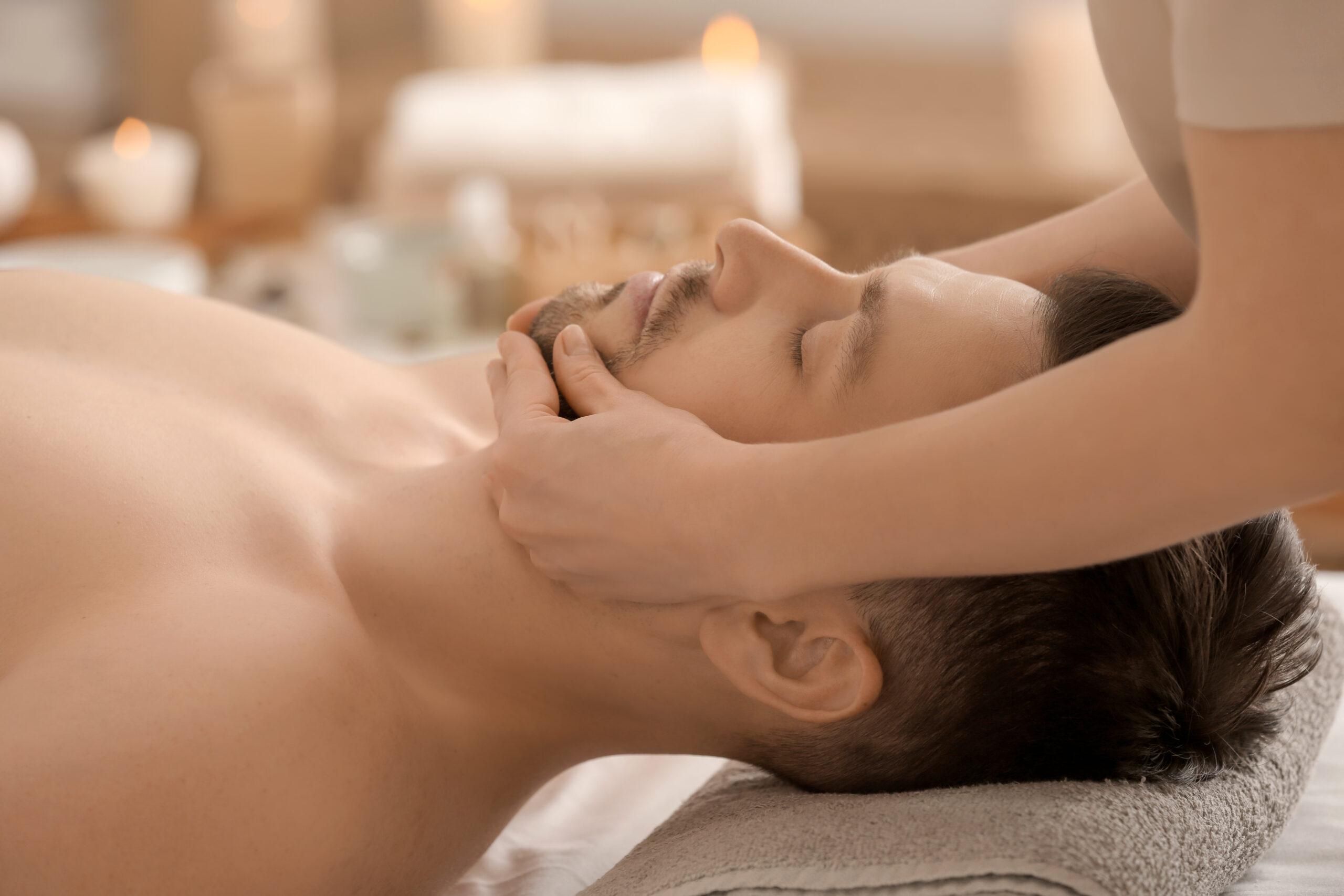 handsome man having facial massage in spa salon