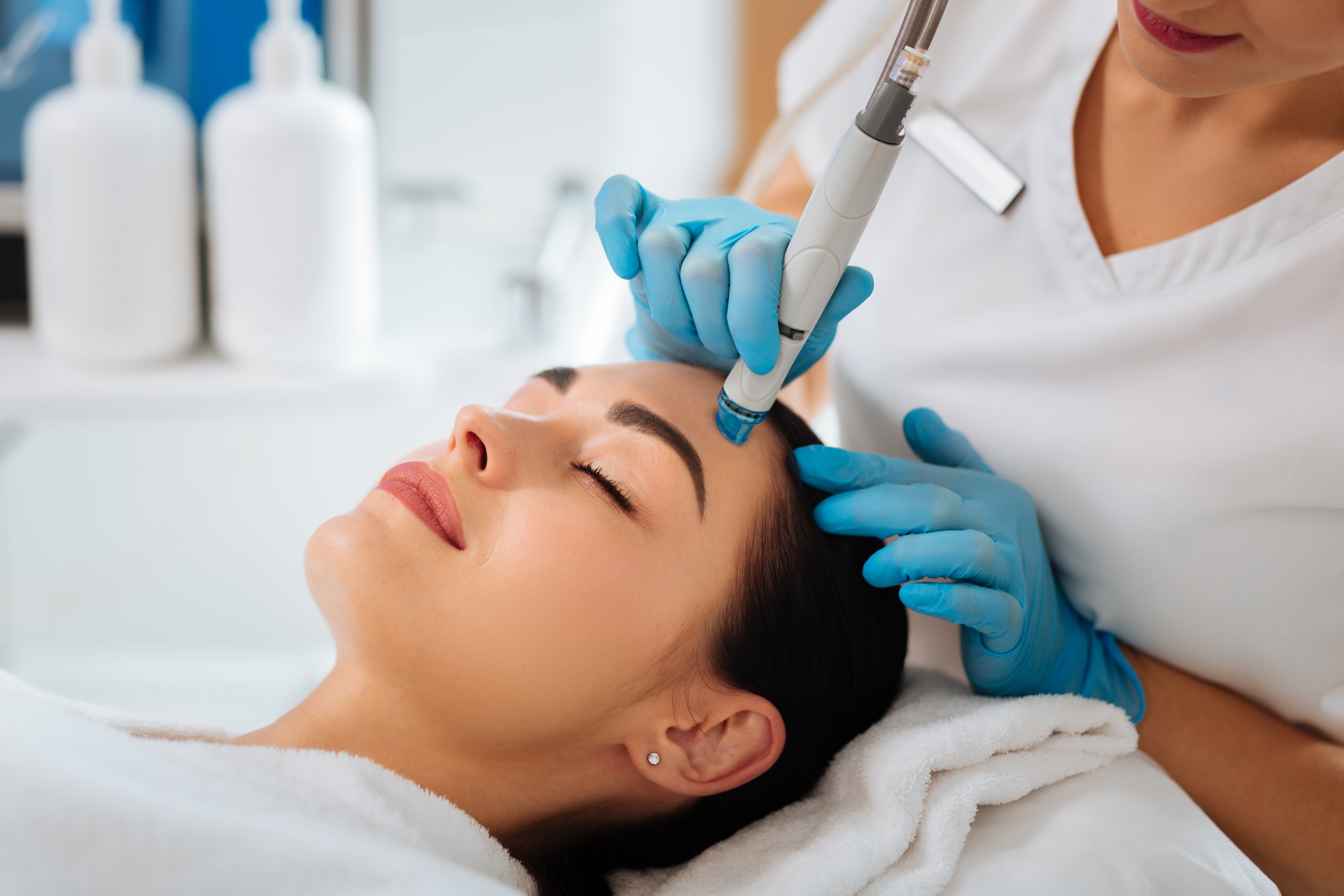 smart skilled female cosmetologist using modern device