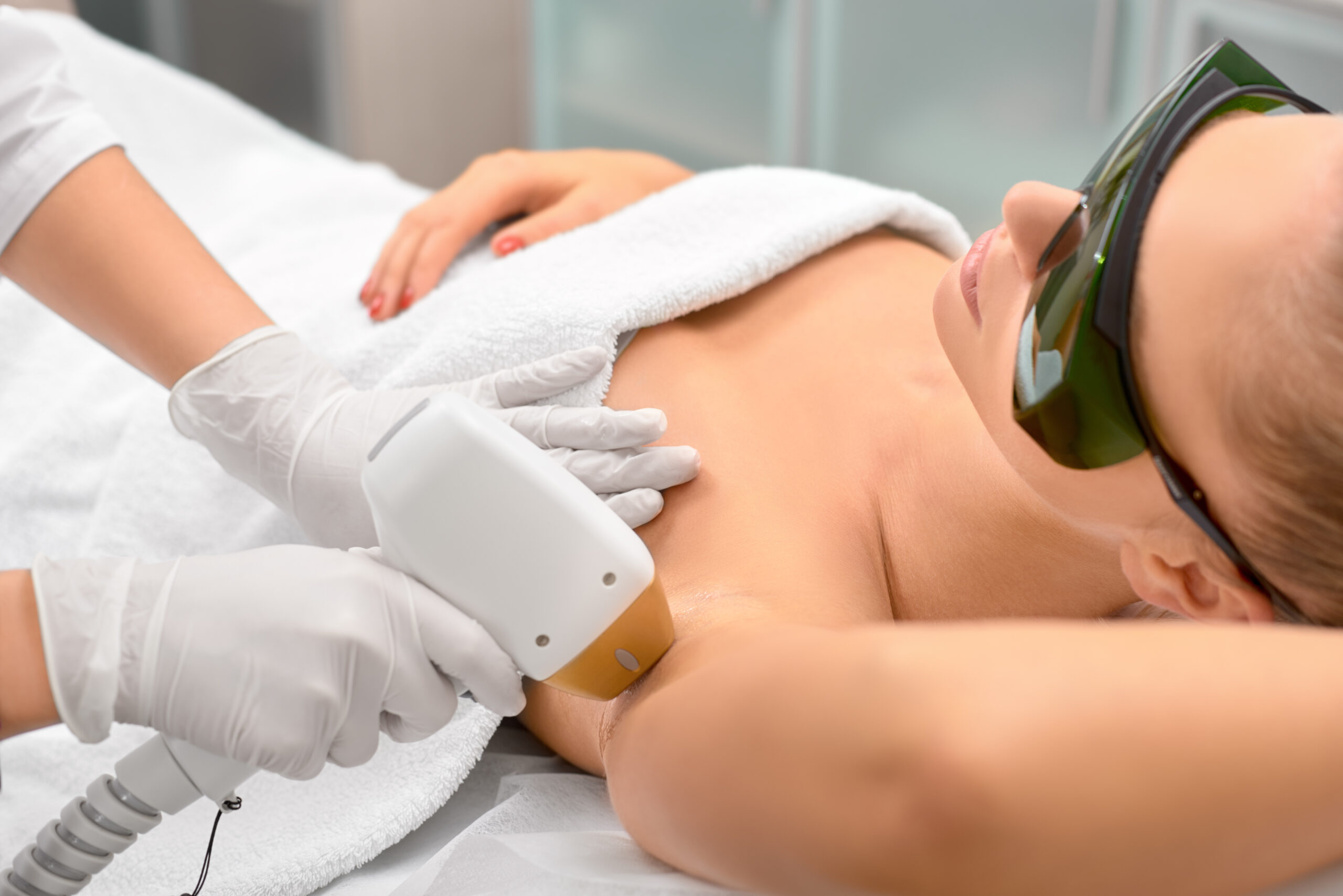 hair removal cosmetology procedure from a therapist at cosmetic beauty spa clinic. laser epilation underarm.